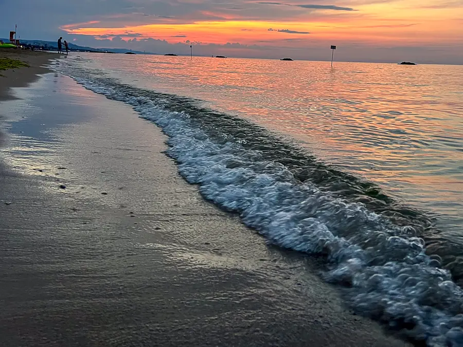 Onde sulla battigia all'alba, con il cielo arancio sull'Adriatico