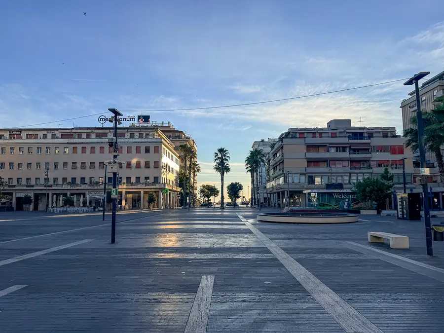Piazza Salotto all'alba, vuota e silenziosa, con le palme e i palazzi